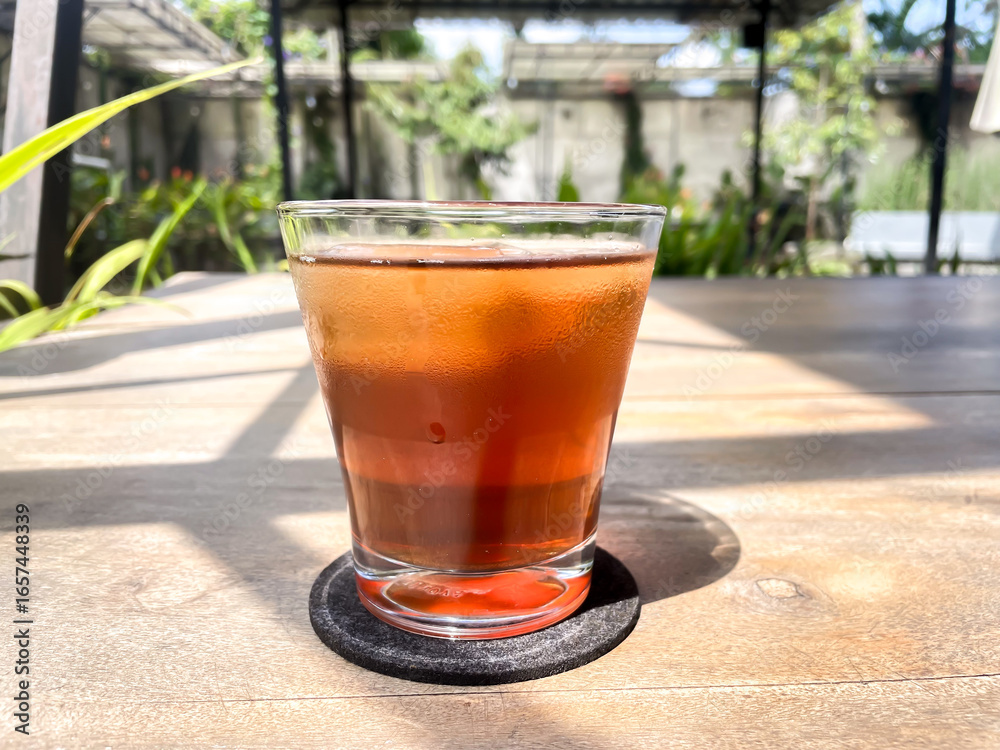 Refreshing Glass of Iced Tea on a Wooden Table in Bright Outdoor Light Refreshing Glass of Iced Tea on a Wooden Table in Bright Outdoor Light