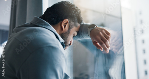 Frustrated, businessman and window with stress for bankruptcy, company liquidation or financial crisis at office. Burnout, man or employee with anxiety, strain or pressure for debt mistake or failure
