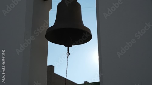 The ringing of bells. Large metal bell hangs on  chain outside the temple.