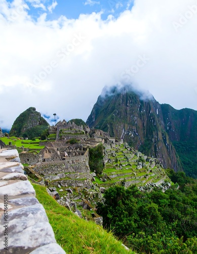 Ancient stone ruins nestled in a lush green valley, partially obscured by mist-covered mountains
