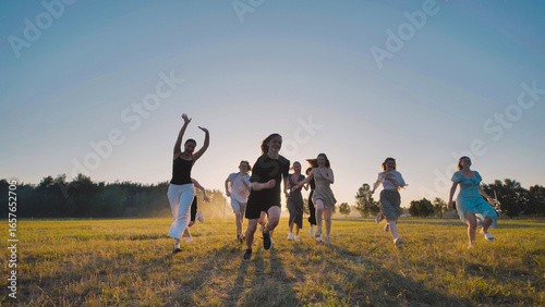 High school students are happily frolicking in a field at sunset, embracing the carefree joy of their summer vacation