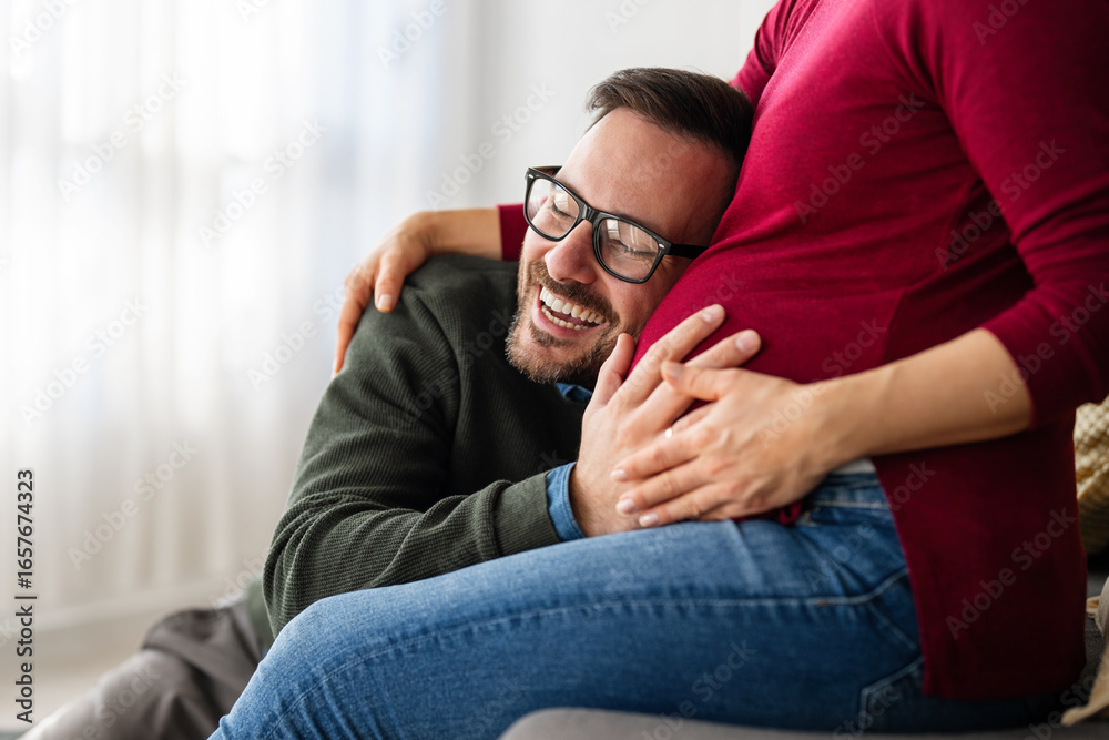 Obraz premium Beautiful pregnant woman and her handsome husband are smiling while spending time together at home