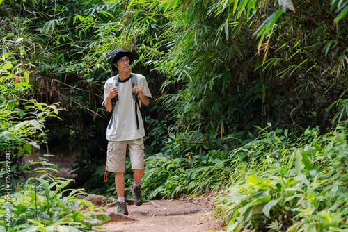 Quadro su tela Young male hiker exploring lush green tropical forest trail
