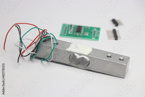 Load cell module with amplifier on the background with unsoldered pins on a white background