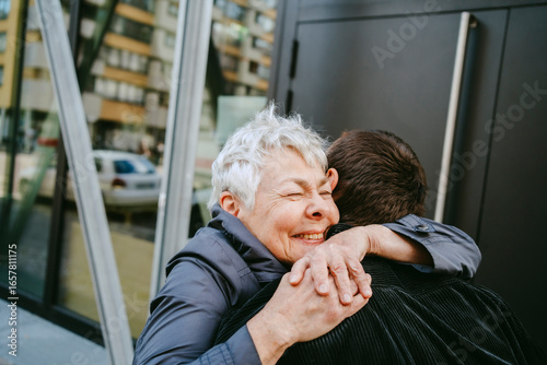 Mother and son hugging outdoors in the city.