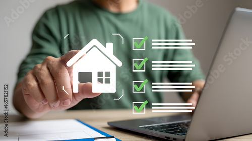 Person holding a house icon with a checklist and laptop in the background