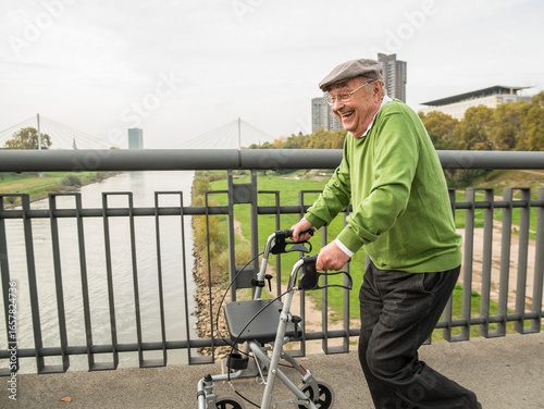 Playful senior man with wheeled walker on bridge