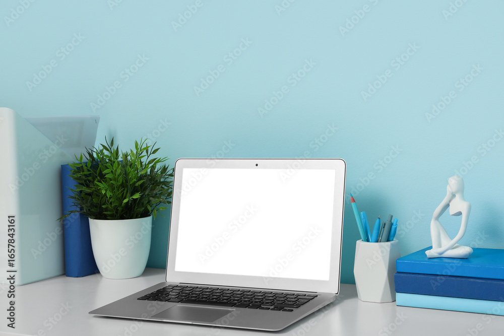 Obraz premium Modern workplace with laptop, stationery and books in light office