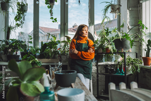 Thoughtful botanist leaning on window sill in plant store