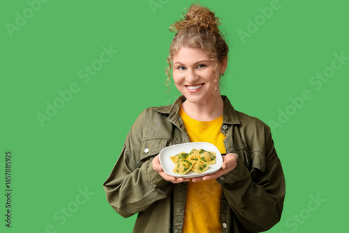 Papier peint Happy young woman with plate of tasty ravioli on green background