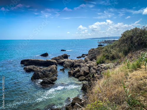 Traditional wooden fishing platform standing on rocky coastline, Adriatic Sea stretching beyond Rocca San Giovanni's scenic Abruzzo landscape