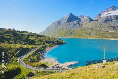 The Bernina railway line and the Alpine Lake Lago Bianco near the Bernina Pass, in the canton of Graubünden (Grisons), Switzerland