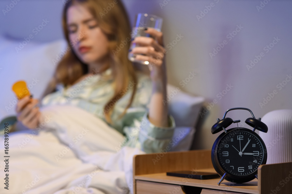 Alarm clock on table of woman taking sleeping pills in bedroom at night, closeup Alarm clock on table of woman taking sleeping pills in bedroom at night, closeup