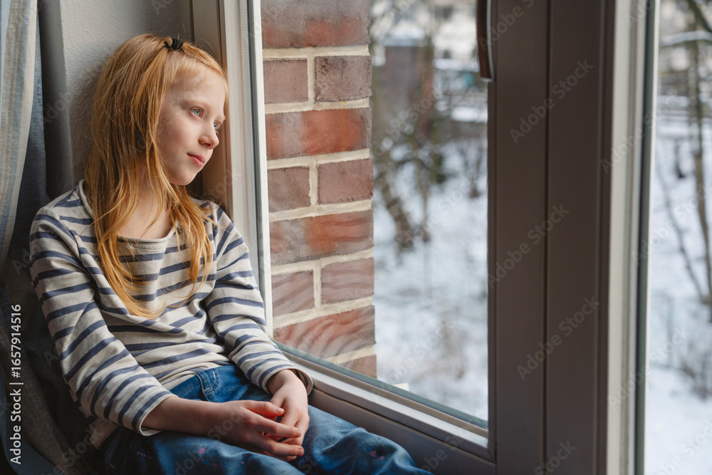 Redhead girl looking out of window at home Redhead girl looking out of window at home