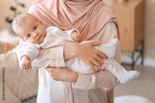 Muslim mother in hijab with cute little baby at home, closeup