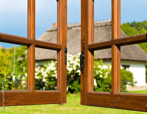 Wooden windows overlooking a thatched-roof cottage
