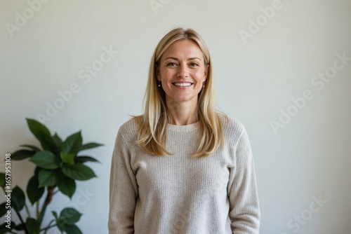 Joyful portrait of a beautiful middle-aged Scandinavian woman with blonde hair, smiling confidently against a plain white studio background.