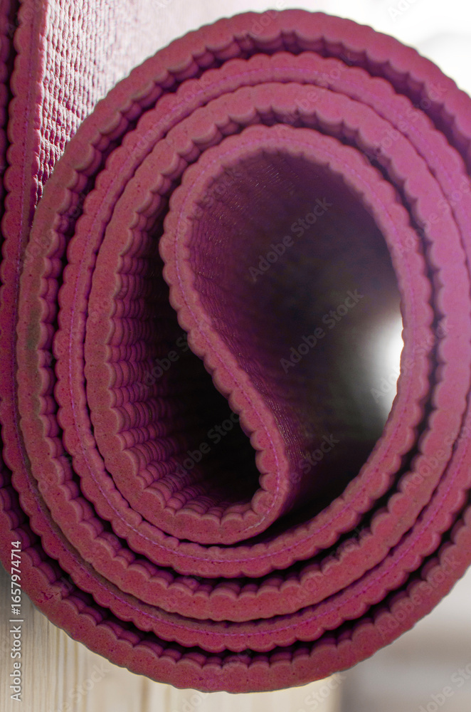 Obraz premium vertical shot of a rolled-up magenta yoga or exercise mat, highlighting its texture and color..