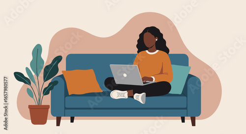 African American woman comfortably works remotely on laptop from a cozy couch, illustrating telework, freelancing, and digital connectivity.