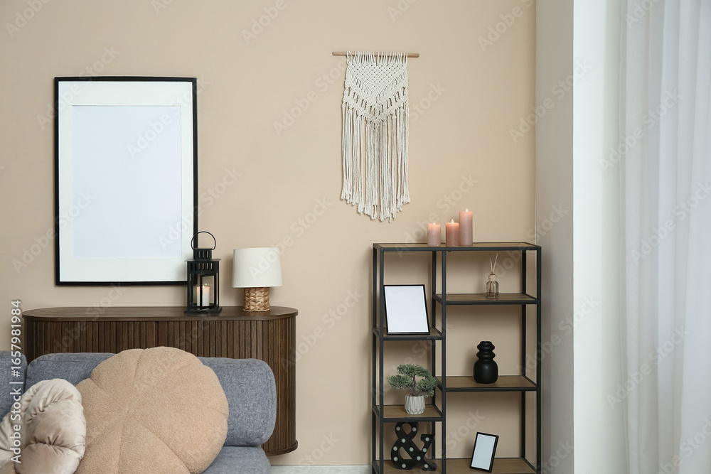 Fototapeta premium Interior of light living room with chest of drawers and shelving unit near beige wall