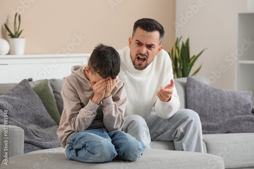 Father with his son squabbling on sofa at home