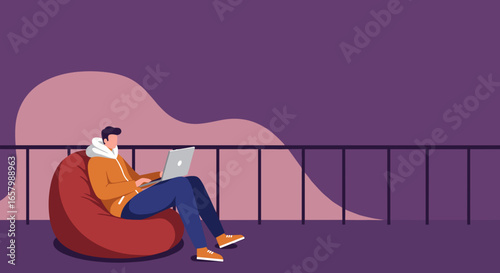 Young man in a hoodie comfortably working on a laptop from a bean bag chair. Ideal for remote work, study, freelancing, or casual lifestyle themes.