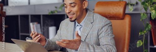 Fotografi A man engaged in an online meeting at a stylish office, showcasing professionalism and collaboration