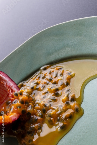 Fruit and juice spilling out of a halved passion fruit on a plate