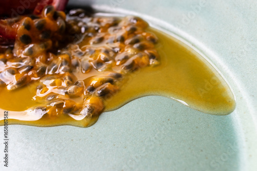 Fruit and juice spilling out of a halved passion fruit on a plate