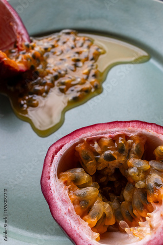 Fruit and juice spilling out of a halved passion fruit on a plate