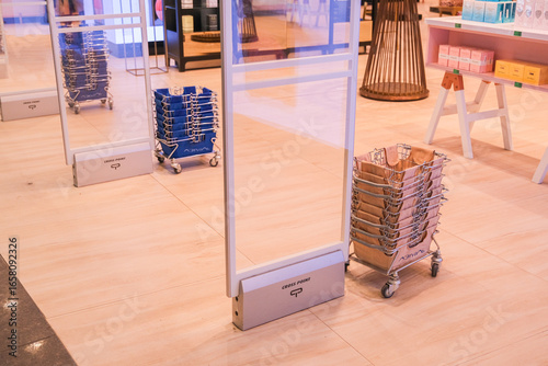 Security gate at store entrance with shopping baskets on wheels. Retail anti-theft system. Shop safety and prevention.