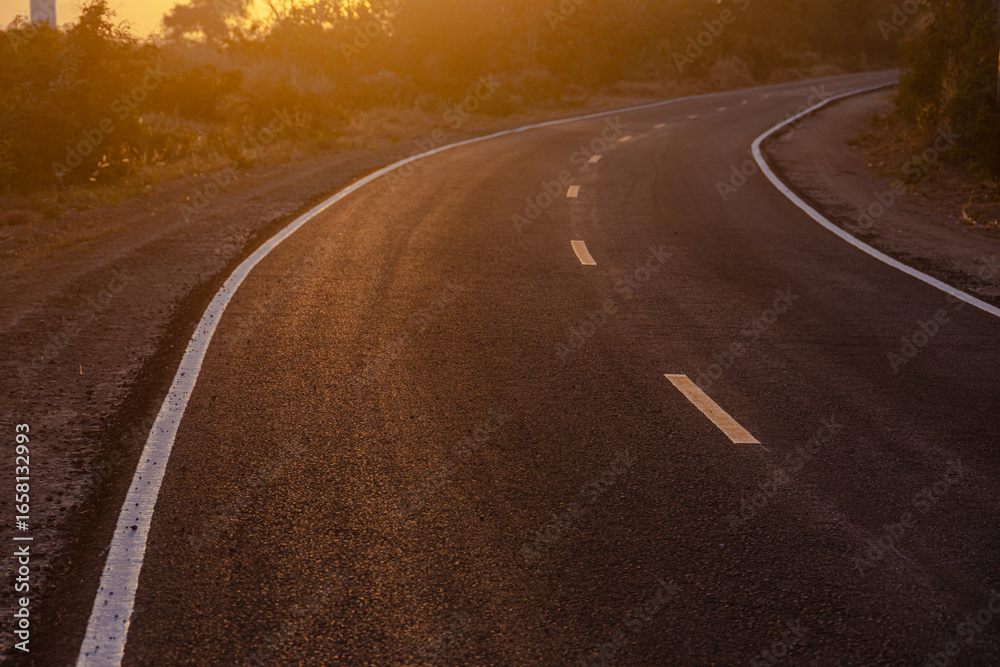 Fototapeta premium Black asphalt curve road, two lane curved along way path forward at countryside sunset sky