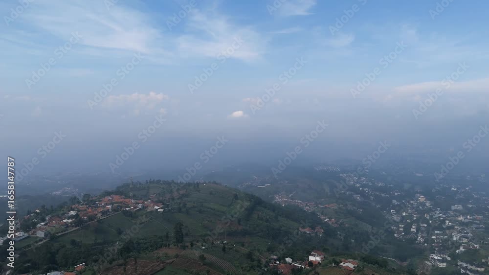 Aerial View of Rolling Green Hills and Distant Cityscape on a Misty Morning Aerial View of Rolling Green Hills and Distant Cityscape on a Misty Morning