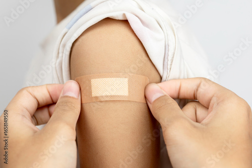 Applying adhesive bandage plaster on an arm after vaccination. Medical, healthcare, and immunization concept.