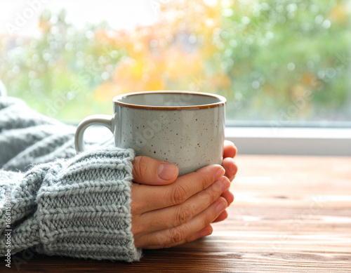 Cozy Hands Holding Speckled Mug by Window on Wooden Table