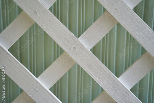 Decorative White Wooden Lattice with Diagonal Pattern on a Green Wall