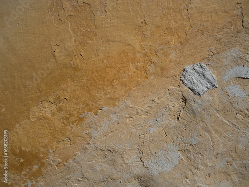 Detailed Texture of a Rough and Cracked Yellow Plastered Wall

