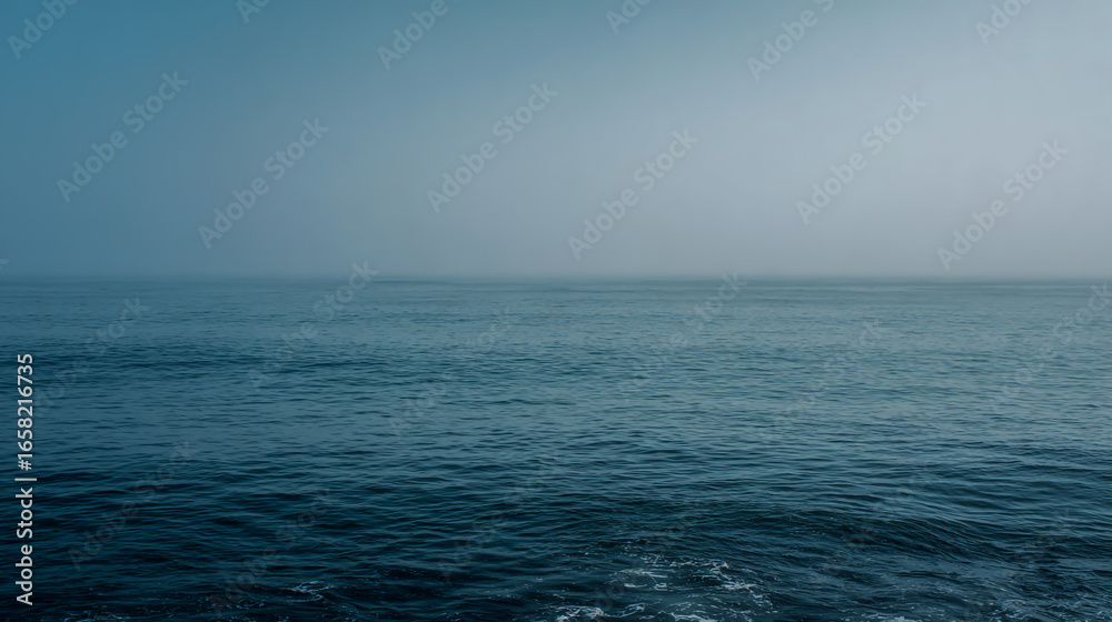 Obraz premium Misty ocean horizon with blue and gray water under a calm sky, tranquil seascape, soft atmospheric lighting, high-resolution.