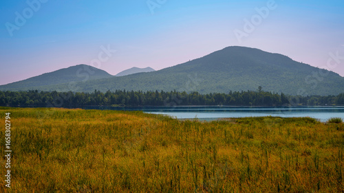 Early autumn landscape over Flagstaff Lake and marshland in Maine with water reflections of the mountains, tranquil beauty in the heart of New England’s seasonal transition.