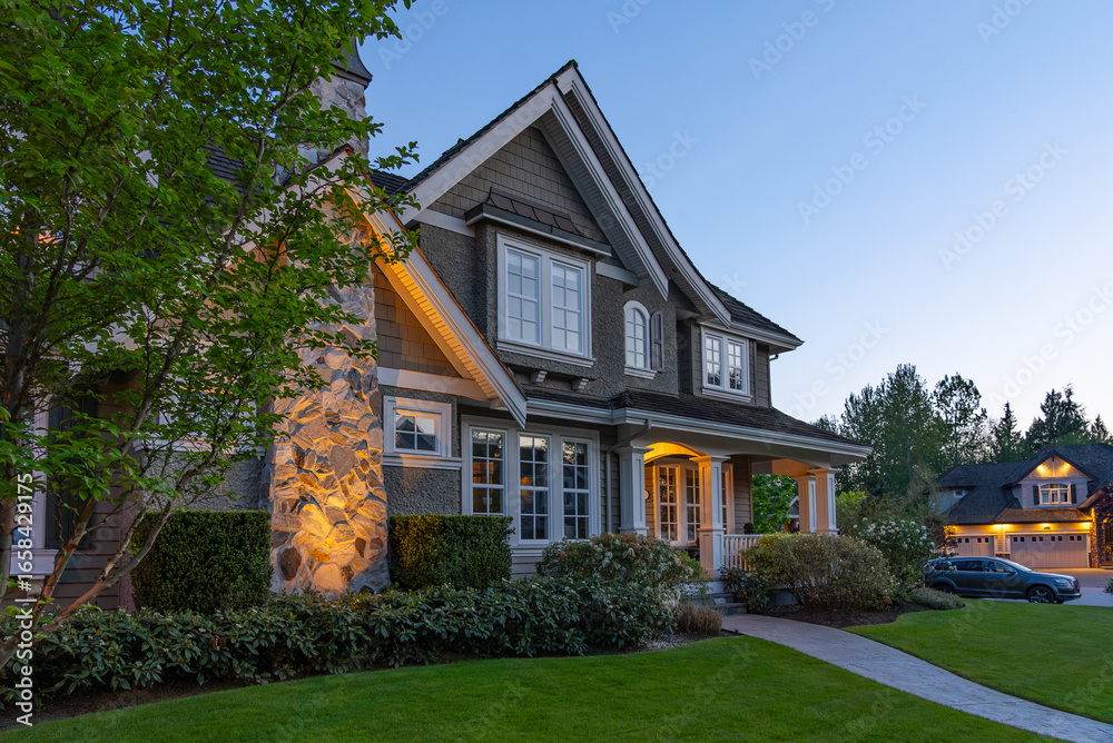 Obraz premium Two story stucco luxury house with nice Spring blossom landscape at night in Vancouver, Canada, North America. May 2025.