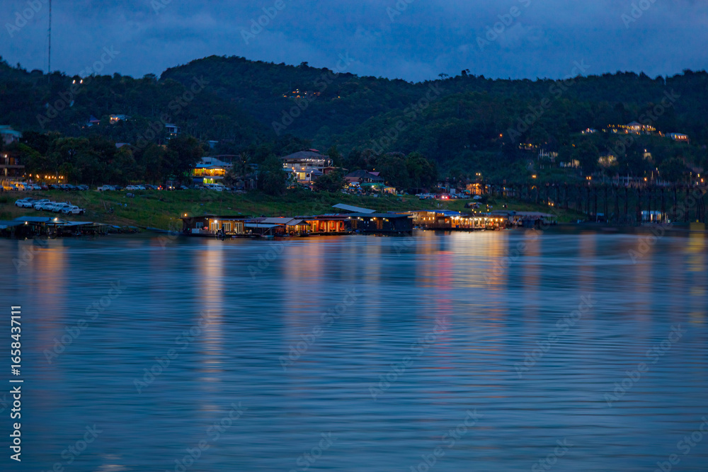 Naklejka premium The Mon village in Kanchanaburi with morning mist on the green mountains and clear river.