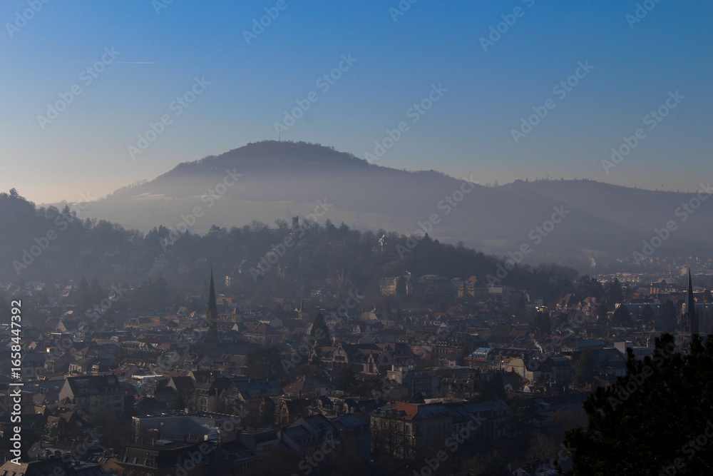 Obraz premium Panoramic view of the foggy city of Freiburg with snow-capped mountain peaks in the background on a winter day 