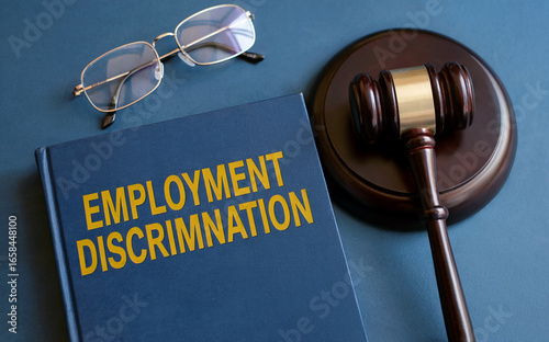 Legal concept of employment discrimination and workplace justice, with a law book, judge's gavel, and glasses on a desk.
