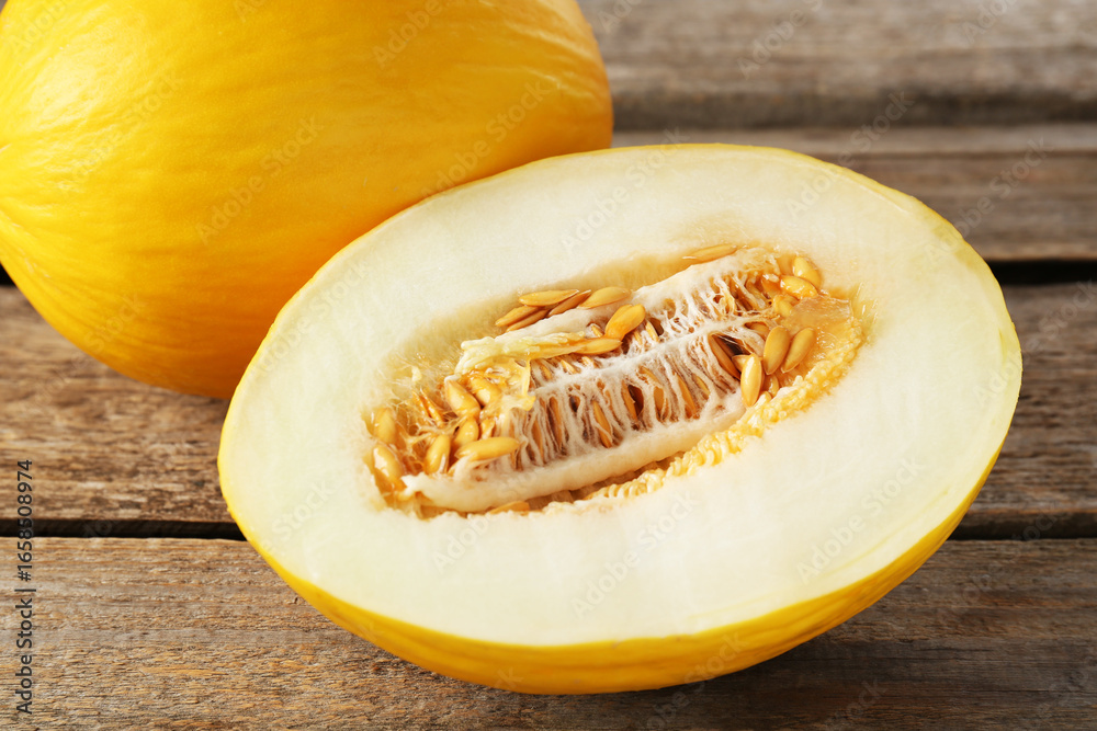 Cut and whole ripe melons on wooden table, closeup Cut and whole ripe melons on wooden table, closeup