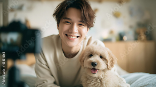 Smiling young youtuber man cuddling a pet dog at home