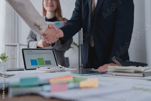 Foto Business partners shaking hands in a modern office after a successful meeting, c