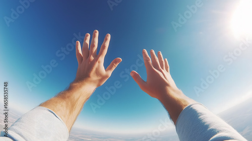 Point of view of skydiver with hands outstretched in clear blue sky - Surrealism
