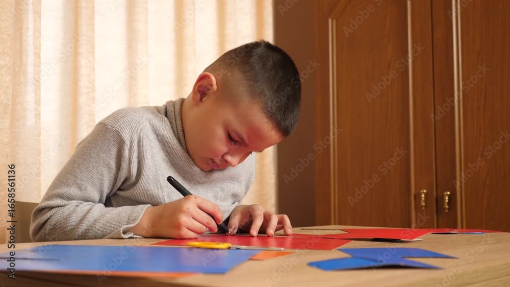 A boy makes a craft from colored cardboard. Hobbies and leisure. A boy makes a craft from colored cardboard. Hobbies and leisure.