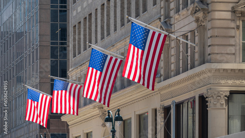 Photography Four American flags waving on the facade of a building on a sunny day
