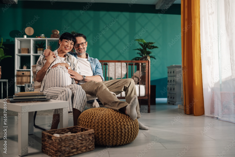 Obraz premium Happy couple expecting baby relaxing in nursery